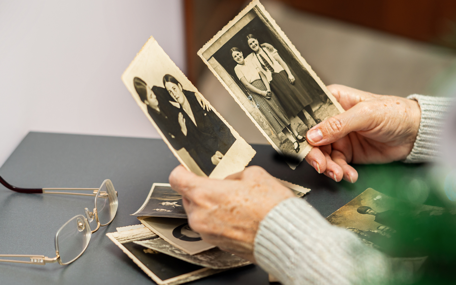Senior hands holding old family photos while downsizing memories in North County San Diego